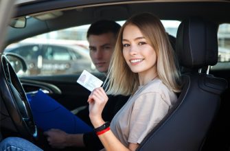joyful girl driving training car with drivers license card her hands